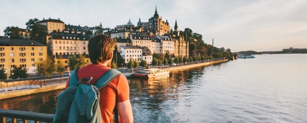 A student stands on a bridge enjoying the view of the water beside Stockholm, Sweden