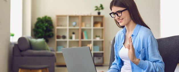 Girl saying high in front of laptop during a virtual meeting