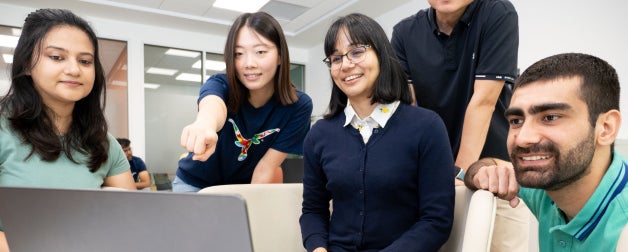 ISSS students smile while looking at a laptop screen