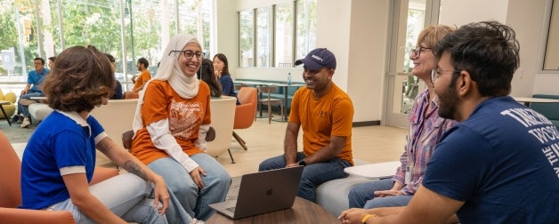 Smiling UT students sit together and talk in the Texas Global lounge