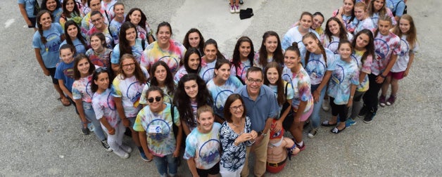 A group of school children in colorful shirts stand in a heart formation in North Macedonia