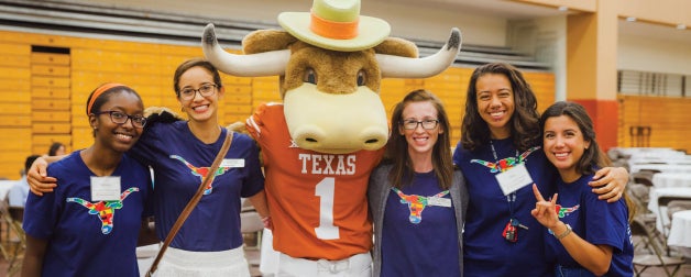 female longhorns in texas global shirts smile and pose with the UT longhorn mascot