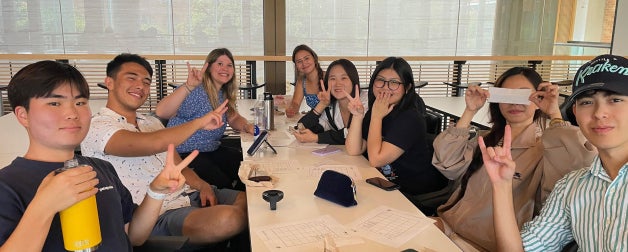 ELC students smile while displaying the Longhorn hook'em sign at a murder mystery lunch social event