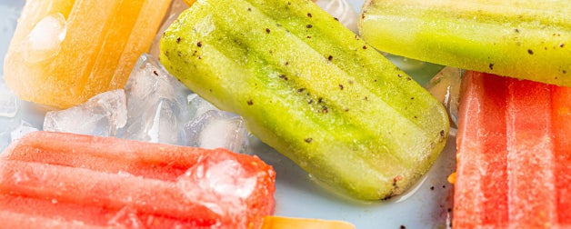 yellow red and green fruit-based icepops are displayed on top of ice