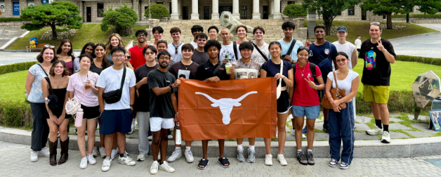 Take the World by the Horns program participants standing in front of building with Longhorn flag