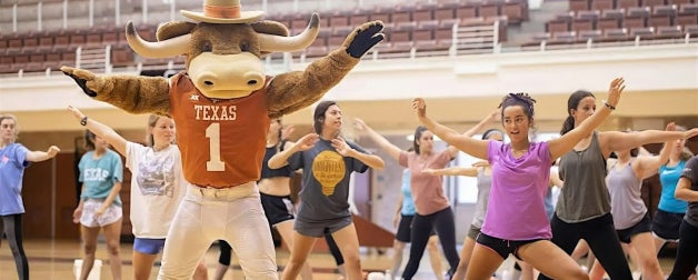 Students participate in a pilates class with the Bevo mascot in the Gregory Gym at UT Austin