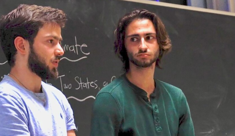 Truman Scholar Elijah Kahlenberg speaks in front of a chalkboard with colleague Jadd Hashem