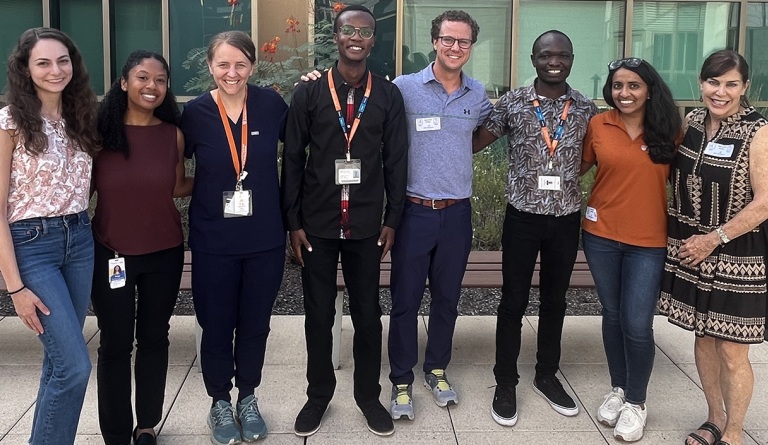 Eight smiling medical students and faculty members stand together