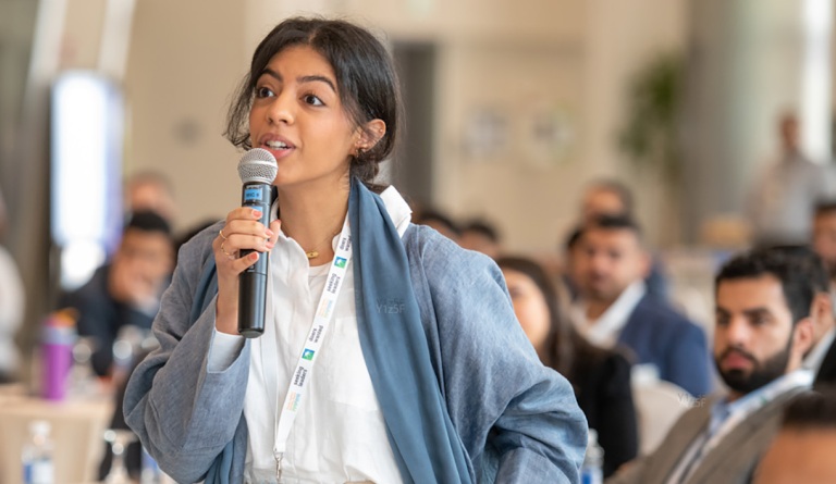 UT alum Leena Alali speaks on a mic at a YLAB gathering