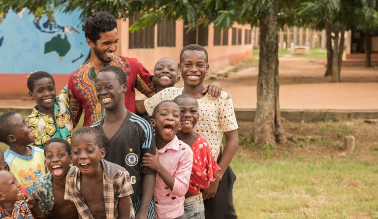 A Peace Corps volunteer laughs with several children