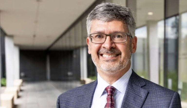 UT Austin Dean of Engineering Roger Bonnecaze smiles in a gray jacket and red tie