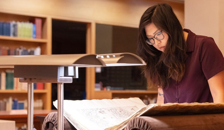 A researcher bends over a manuscript at the Harry Ransom Center