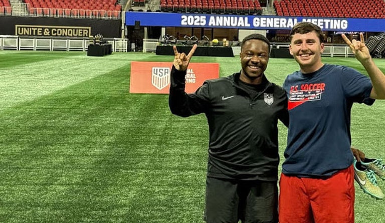 Two men hold up a "hook 'em" hand sign at the World Cup.