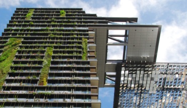 Looking upward at a high-rise building with greenery built into the building's sides.