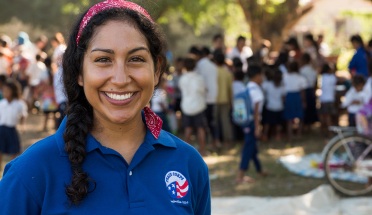 A Peace Corps Volunteer poses in front of members of her community during her service