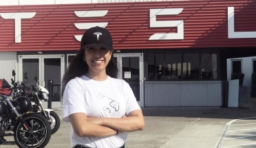 UT student Alejandra Hernandez poses for the camera in front of a TESLA store 