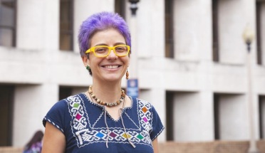 UT Student Yenibel Ruiz poses with a smile and short, bright purple hair. 