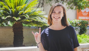 a girl poses with a hook em hand sign 