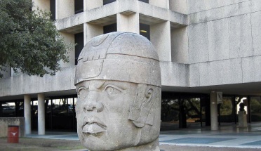 the olmec head statue in front of a building on campus