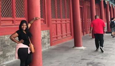 a girl poses with a red building in china