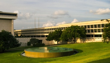 large building with trees and fountain in front