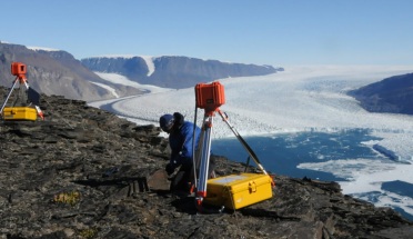people near scientific equipment work near frozen body of water and mountains during daytime