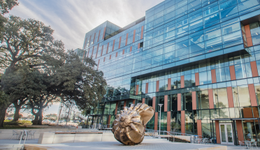 a view of the dell medical school building with a shell sculpture in front 