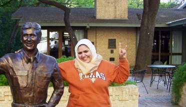 walaa ali smiles and poses with a statue on campus 