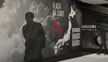Human shadows walk by the photo exhibit Flash of Light, Wall of Fire at the Briscoe Center for American History