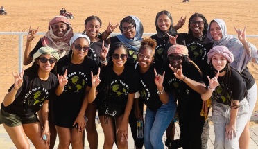 Students from the Fearless Leadership Institute smile for a group picture in front of sand dunes