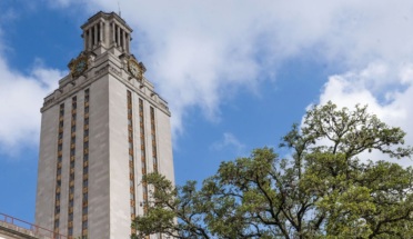 UT Tower with treetop against blue sky with clouds