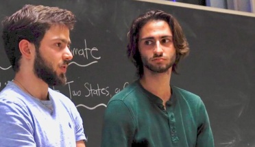 Truman Scholar Elijah Kahlenberg speaks in front of a chalkboard with colleague Jadd Hashem