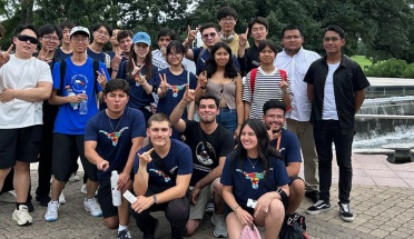 Global Summer Institute students throw the Hook 'em sign by a fountain