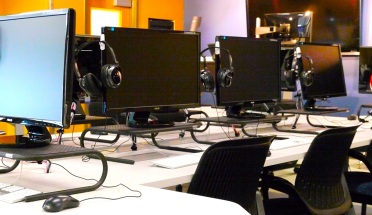 Computer monitors and headphones in Moody College's multimedia classroom