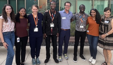 Eight smiling medical students and faculty members stand together