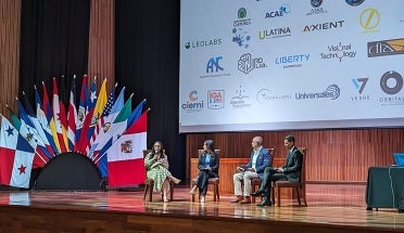 UT alum Alina Nassar speaks on a stage adorned with flags of the world