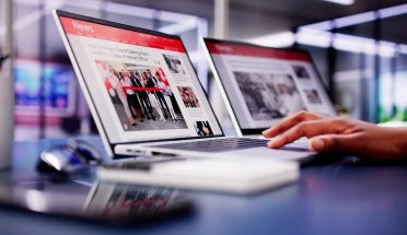 Hand types on a laptop displaying a news site