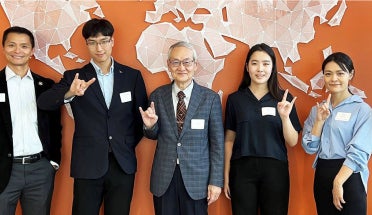 People pose in front of while and hold up "hook em" sign. 