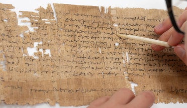 a researcher writes on ancient papyrus paper