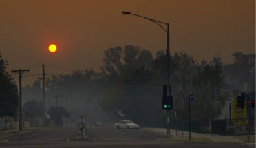 The sun sets over a hazy orange sky.