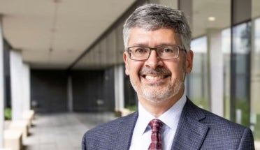 UT Austin Dean of Engineering Roger Bonnecaze smiles in a gray jacket and red tie