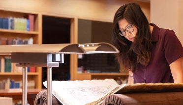 A researcher bends over a manuscript at the Harry Ransom Center