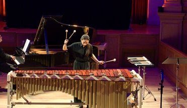 A woman plays a marimba in a music performance hall.