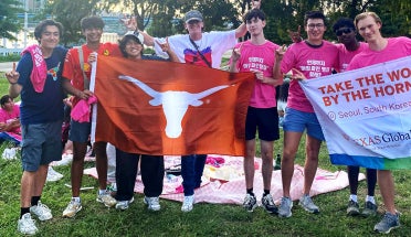 Students with Take the World by the Horns unfurl a Longhorn flag in Seoul