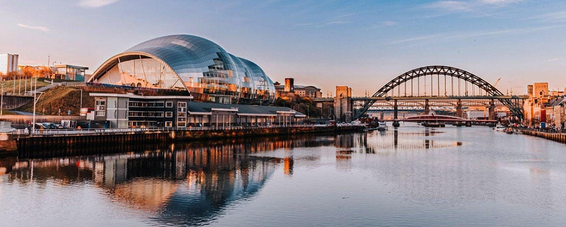 an interesting building along a river with an arched bridge in the background