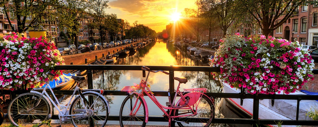 A beautiful image of sunset over canal with colorful bikes in the foreground