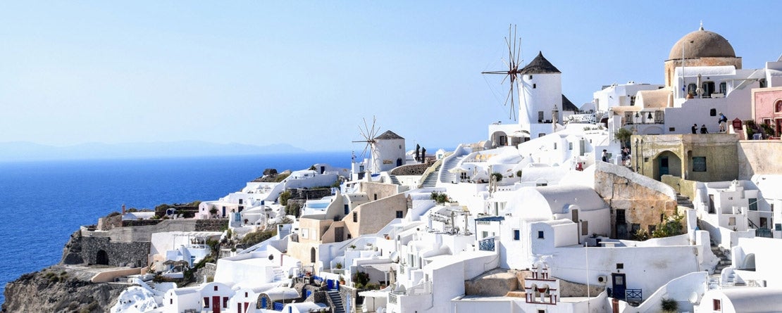 A beautiful view of the white washed buildings in Santorini Greece as they cascade down towards the ocean