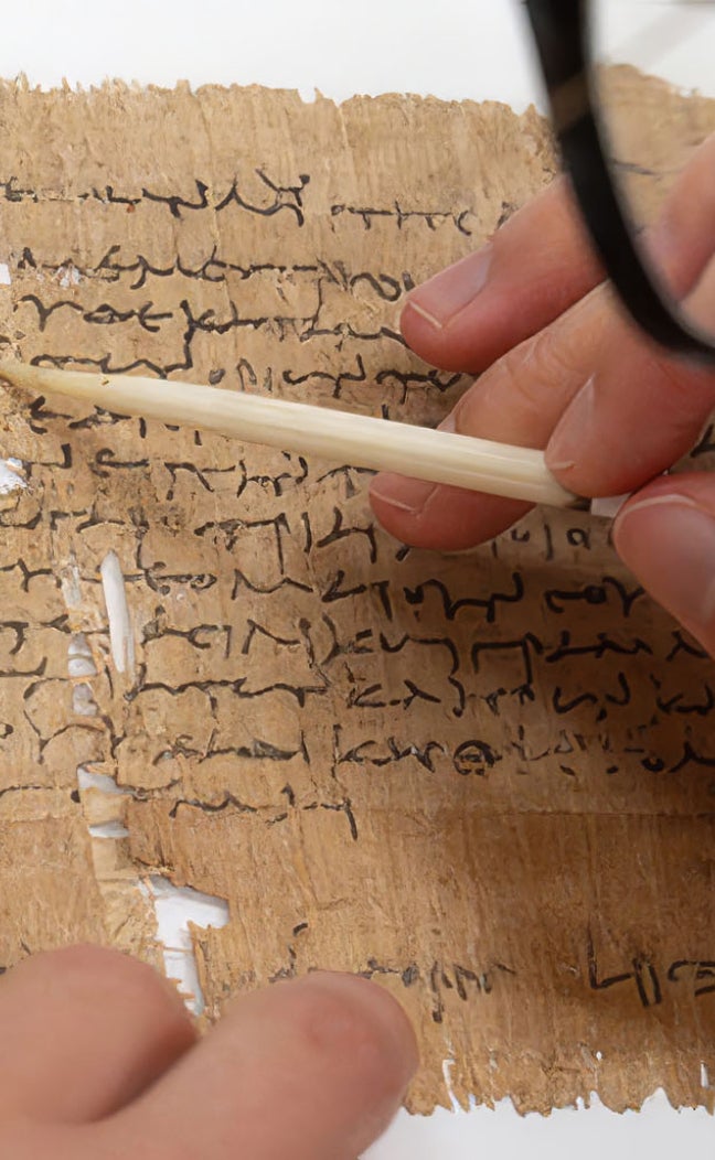 a researcher writes on ancient papyrus paper
