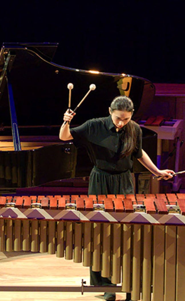 A woman plays a marimba in a music performance hall.