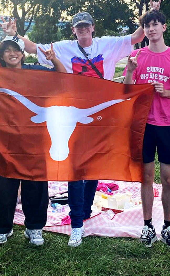Students with Take the World by the Horns unfurl a Longhorn flag in Seoul